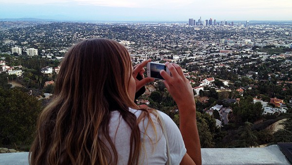 Photo of Ida Bohlin on the balcony at the Griffith Park Observatory taking a cell phone photo of the Los Angeles skyline