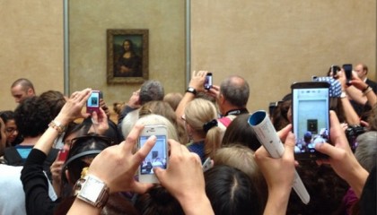 photo of hands holding cell phones in the air to try to photograph the Mona Lisa at The Louvre in Paris