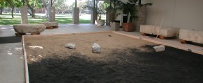 Photo of Glenn Zucman's "Zen Entropy Garden" (a large "zen garden" / sandbox with half white sand, and half black sand, and rakes that let visitors create their own zen garden configurations as they also mix the sand into an entropic grey) installed in the CSULB School of Art, Art Gallery Courtyard