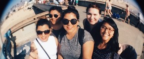 5 college women, 3 in big, dark sunglasses, stand on the beach at Venice Beach, CA and take a summer selfie