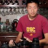 photo of Evan Huang at a table with cameras and lenses in front of him