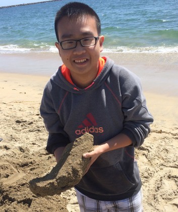 Khoa Do  holding a plaster casting of his foot at the beach