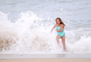 a young girl runs from a crashing wave at Seal Beach, CA